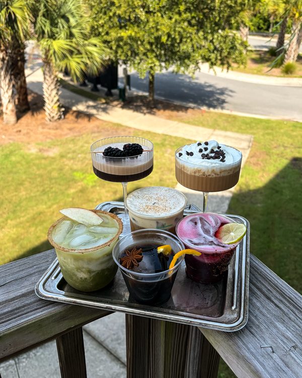 A tray of specialty coffee mocktails and lattes on a balcony